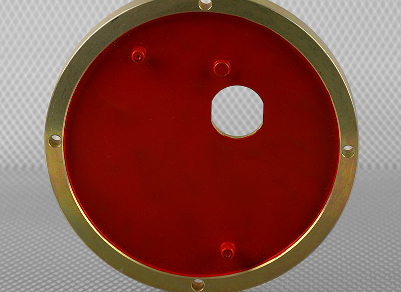 Red masking lacquer covering the centre of a gold metal part